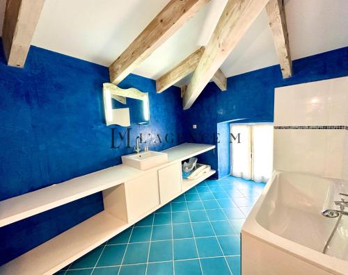 La salle de bains est pourvue de murs bleus, d'un lavabo et d'une baignoire. dans l'établissement Maison golf de calvi couchers de soleil vue mer LUMIO, à Lumio