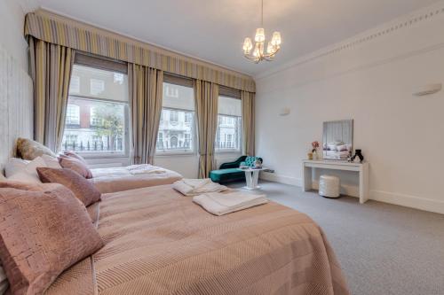 a large bedroom with two beds and a chandelier at Stylish 3 Bedroom Luxury Apartment in Harley St 3 in London