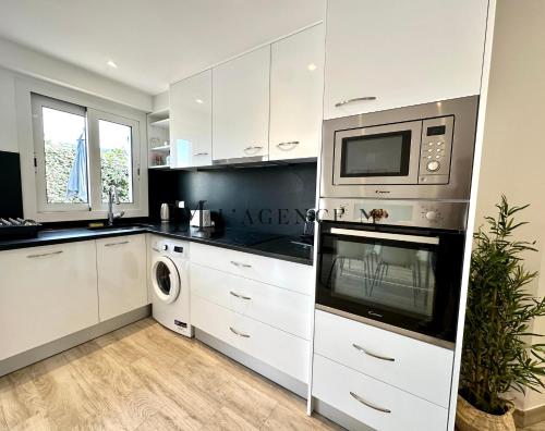 cocina con armarios blancos y microondas en Appartement Saint-Antoine, paisible en Calvi