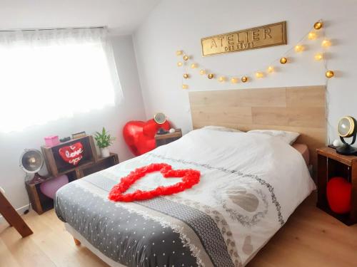 ein Schlafzimmer mit einem Bett mit einem roten Herz darauf in der Unterkunft Location Logement Au Cœur du Vignoble et Spa in La Chapelle-Heulin