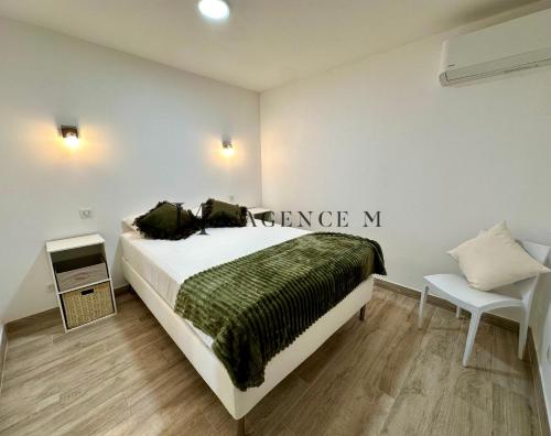 une chambre avec un grand lit avec une couverture verte dans l'établissement Appartement Saint-Antoine Paisible CALVI, à Calvi