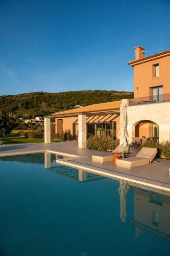 a house with a swimming pool in front of a building at Reveli Suites in Katelios