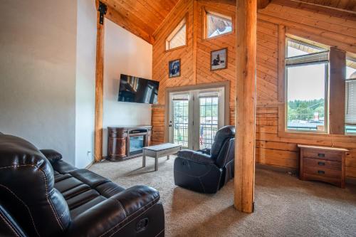 a living room with a leather couch and a television at Alpine Lodge Hotel in Cascade