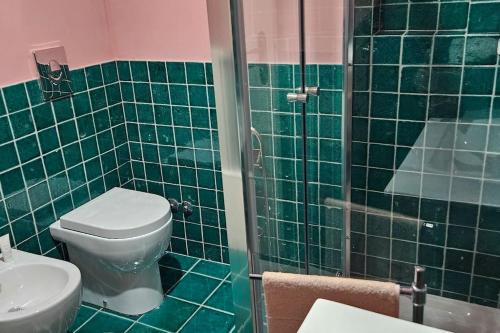 W wyłożonej zielonymi kafelkami łazience znajduje się toaleta i prysznic. w obiekcie Residenza Palazzo Miraldi-Ferrari w mieście Cava deʼ Tirreni