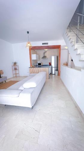 a living room with a white couch and a staircase at Alojamientos Claus in Almodóvar del Río