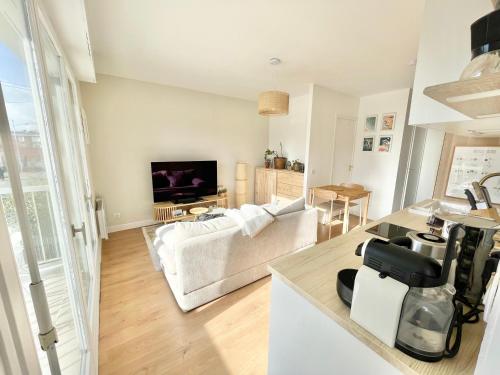 uma sala de estar com um sofá branco e uma televisão em Appartement avec Balcon et place de Parking à Berck Plage em Berck