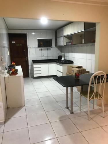 eine Küche mit einem schwarzen Tisch und einem weißen Fliesenboden in der Unterkunft Casa de Temporada no Maior São João do Mundo in Campina Grande