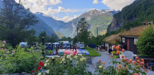 um grupo de pessoas num jardim com montanhas ao fundo em Vinje Camping em Geiranger