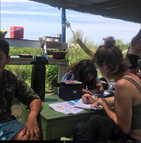 eine Gruppe von Menschen, die an einem Tisch sitzen und unterschreiben in der Unterkunft Darwin Hostel in Cabo Polonio