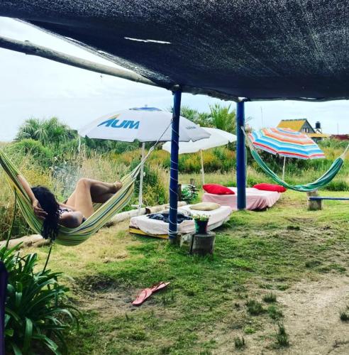 a woman laying in a hammock under an umbrella at Darwin Hostel in Cabo Polonio