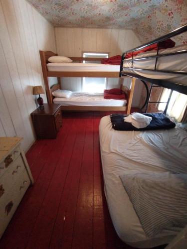 a small room with two bunk beds and a wooden floor at Adirondack Retreat in Bakers Mills