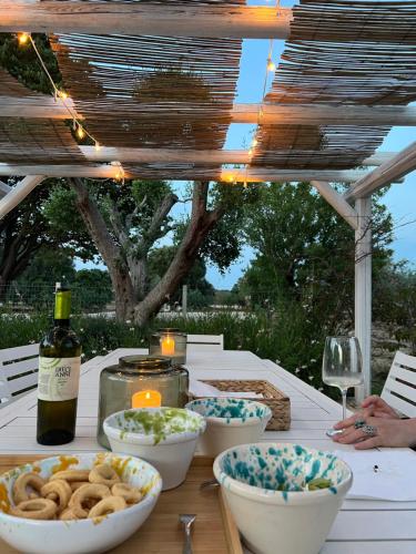 einen Tisch mit Schalen Essen und eine Flasche Wein in der Unterkunft VITA VIVET TRULLO in San Michele Salentino