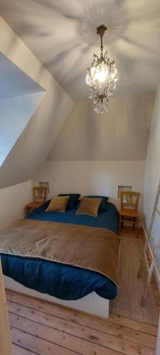 - une chambre avec un lit bleu et un lustre dans l'établissement Maison de maître avec piscine, à Quetteville