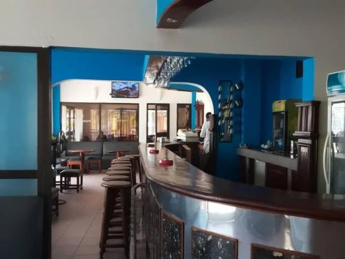 a bar in a restaurant with blue walls and stools at Acropole Hotel in Cotonou