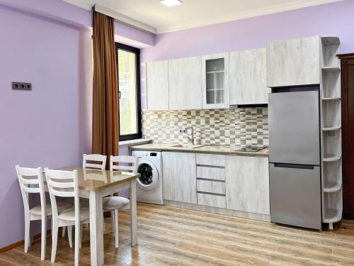 cocina con mesa, sillas y paredes púrpuras en Khidikari Hotel en Ambrolauri