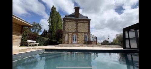 a house with a swimming pool in front of a building at Maison de maître avec piscine in Quetteville