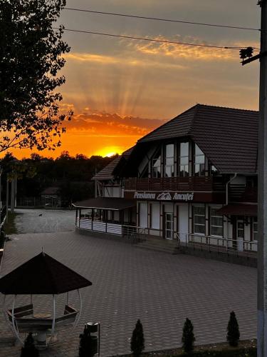 a building with a sunset in the background at Pensiunea Ancuței in Şerpeni
