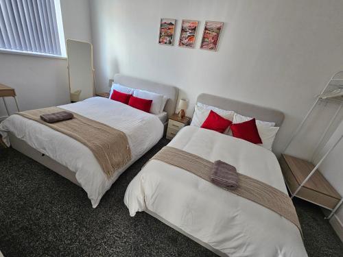 Duas camas num quarto com almofadas vermelhas. em Stylish 1 bed Apartment in Newly Refurbished Building w/ Parking & Wi-Fi em Birmingham