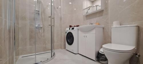 a bathroom with a shower and a washing machine at Apartamentai Mažvydo alėjoje in Klaipėda