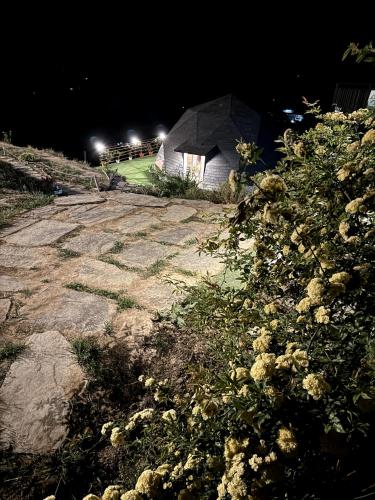 a stone walkway with a building at night at The Soul Stroll Cottages Retreat in Mukteswar