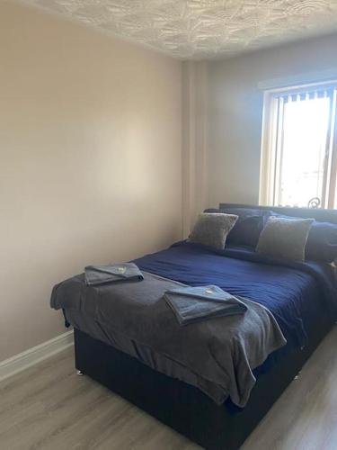 Schlafzimmer mit einem Bett mit blauer Bettwäsche und einem Fenster in der Unterkunft Olympic Place 1-bed Apartment in Rowley Regis