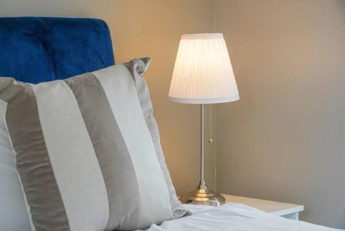 a lamp on a table next to a bed with a pillow at Wavendon Retreat - Sleeps 6 - Driveway Parking, Self-Check-In, Fast Wifi and Smart TV by YOKO PROPERTY in Milton Keynes