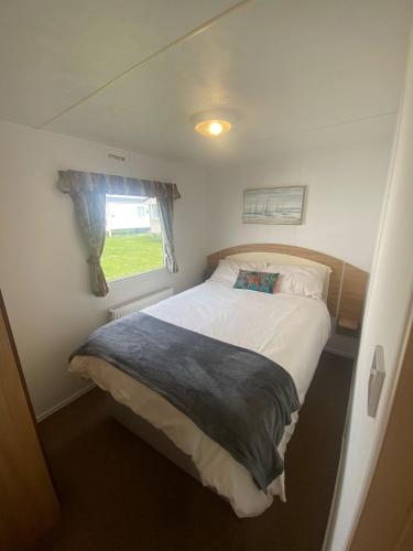 een bed in een kleine kamer met een raam bij 15 Maple Rise in Gristhorpe