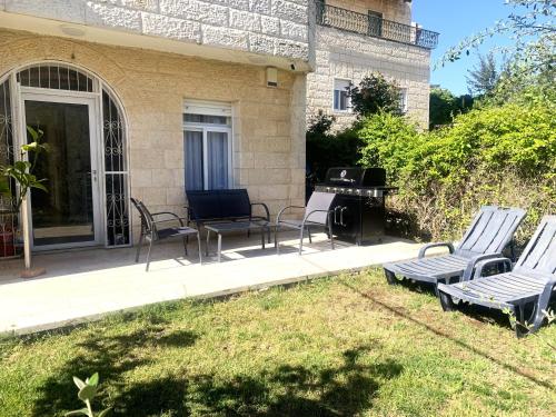une terrasse avec des chaises et un barbecue en face d'une maison dans l'établissement Exclusive Jerusalem Villa, à Giv‘ot Mordekhay