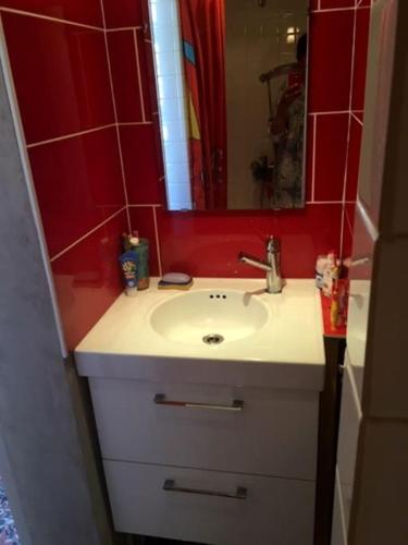 La salle de bains est pourvue d'un lavabo et d'un mur rouge. dans l'établissement Maison bord de mer, à La Tranche-sur-Mer