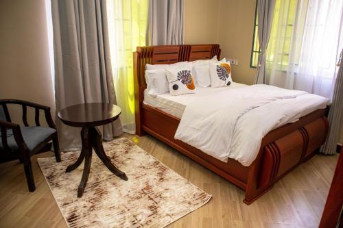 a bedroom with a bed with a table and a chair at Villa Home Apartment Dodoma in Dodoma