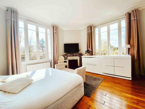 een slaapkamer met een groot wit bed en een televisie bij Superbe appartement proche Disney in Quincy-Voisins