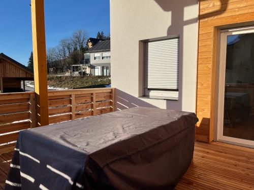 a bed on a wooden deck with a window at Christians Alpenparadies in Bad Mitterndorf