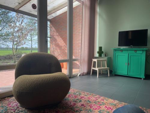 uma sala de estar com uma cadeira e uma televisão em BuitenInn het Overveen em Rijssen