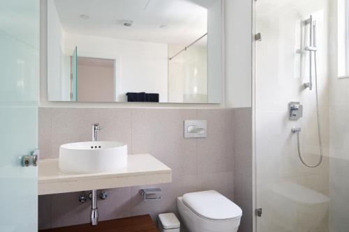 een badkamer met een wastafel, een toilet en een spiegel bij Brandon’s at the Pavilion Cantoments in Accra
