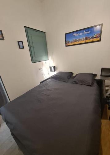 - une chambre avec un lit noir et un panneau mural dans l'établissement Studio avec jardin Rosendael proche plage, à Dunkerque