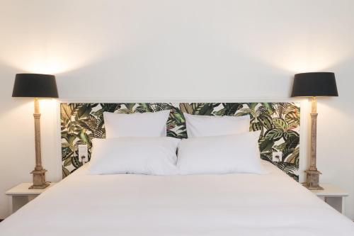 een slaapkamer met een wit bed en 2 lampen bij Demeure de Flore - Hôtel Particulier au Coeur de Brive comprenant 7 appartements de charme in Brive-la-Gaillarde