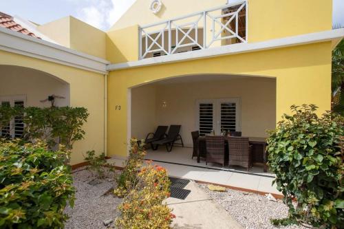 クラレンダイクにあるTrupial F3 Relax & Dive Resort Bonaire Villageの黄色の家(テーブルと椅子付)