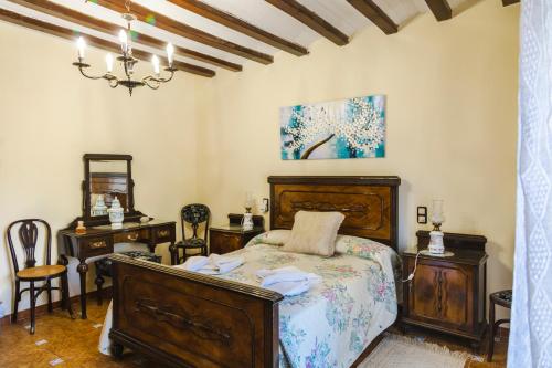 1 dormitorio con 1 cama, 2 mesas y lámpara de araña en CASA CAPITÁN INDALECIO., en Salsadella