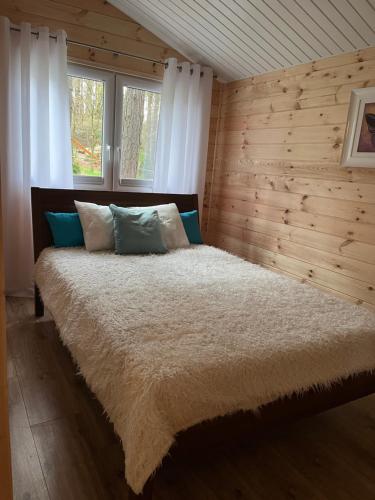 a bedroom with a large bed with wooden walls at Domek obity dechami in Hartowiec