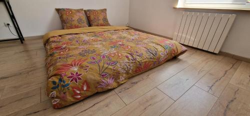 a bed with a colorful comforter in a bedroom at Bel appartement rénové avec de beaux volumes in Flavigny-sur-Moselle