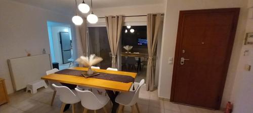 a dining room with a wooden table and white chairs at Rania's house in Aigio