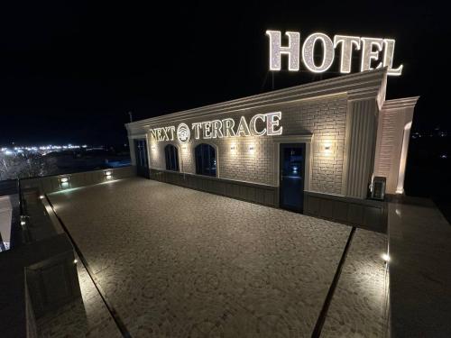 un hôtel la nuit avec un panneau de néon sur lui dans l'établissement Next Hotel Samarkand, à Samarcande