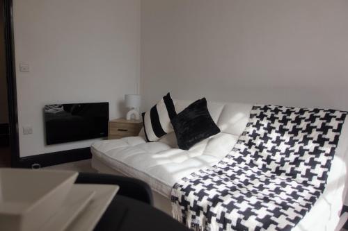 a living room with a white couch with black pillows at 1 bedroom apartment - The Onyx in Cheltenham