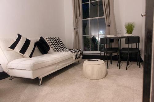 a living room with a white couch and a table at 1 bedroom apartment - The Onyx in Cheltenham