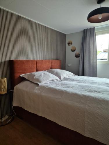 een slaapkamer met een groot bed met witte lakens en een raam bij vakantiehuisje Holterberg in Holten