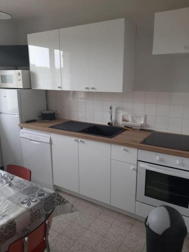 - une cuisine avec des placards blancs, un évier et une table dans l'établissement La maison de Paulette, à Saint-Valery-sur-Somme