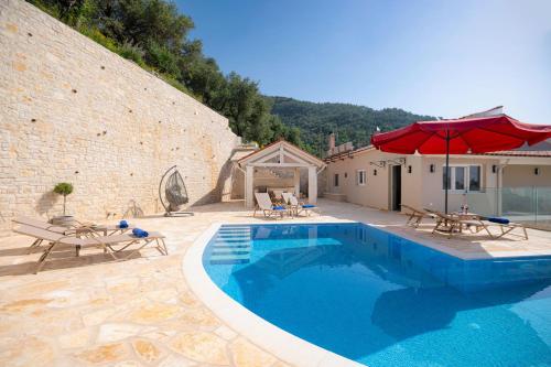 a swimming pool with two chairs and an umbrella at Villa TheView in Katávolos