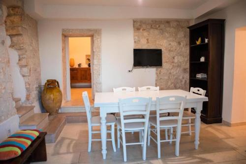 ein weißes Esszimmer mit einem weißen Tisch und Stühlen in der Unterkunft Trullo Masiello in Putignano