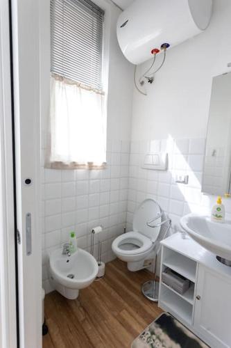 a white bathroom with a toilet and a sink at LOFT 55 Domu de tunì in Ancona
