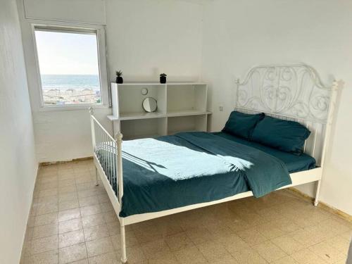 - une chambre avec un lit doté de draps bleus et une fenêtre dans l'établissement Sea Breeze Apartment, à Qiryat Yam